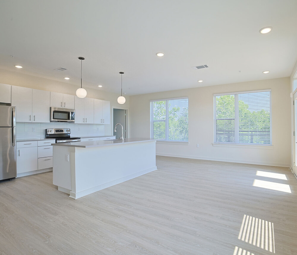 Bright, spacious kitchen with white cabinetry, large island, and stainless steel appliances.